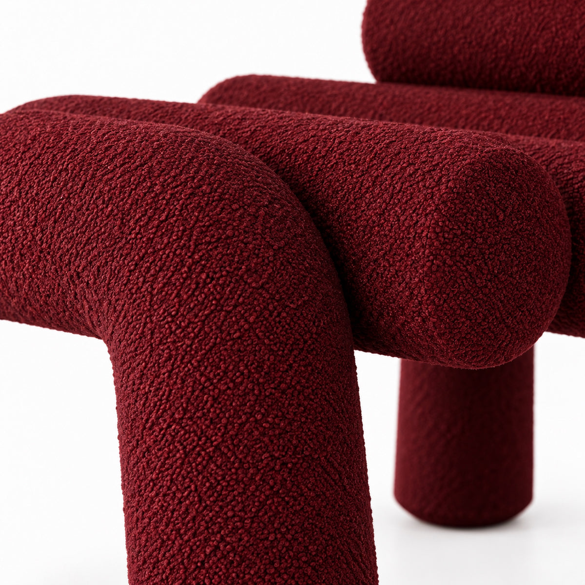 Close-up of Juno Accent Chair burgundy boucle texture where the seat rail meets a leg