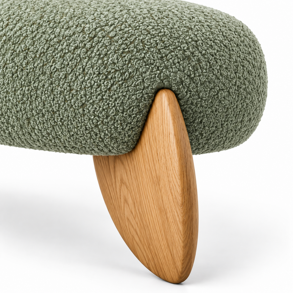 Close-up of sage green boucle meeting a warm oak leaf-shaped leg on the Vela bench