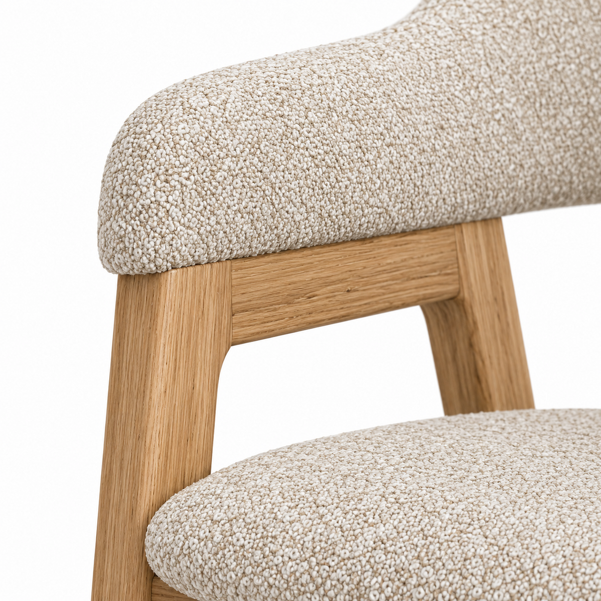 Close-up of oat boucle meeting the warm oak frame on the Anso dining chair