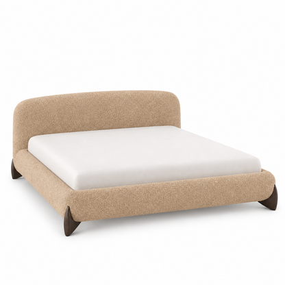 Orma boucle bed frame in caramel-oat with a curved headboard and small angled wood feet, three-quarter view
