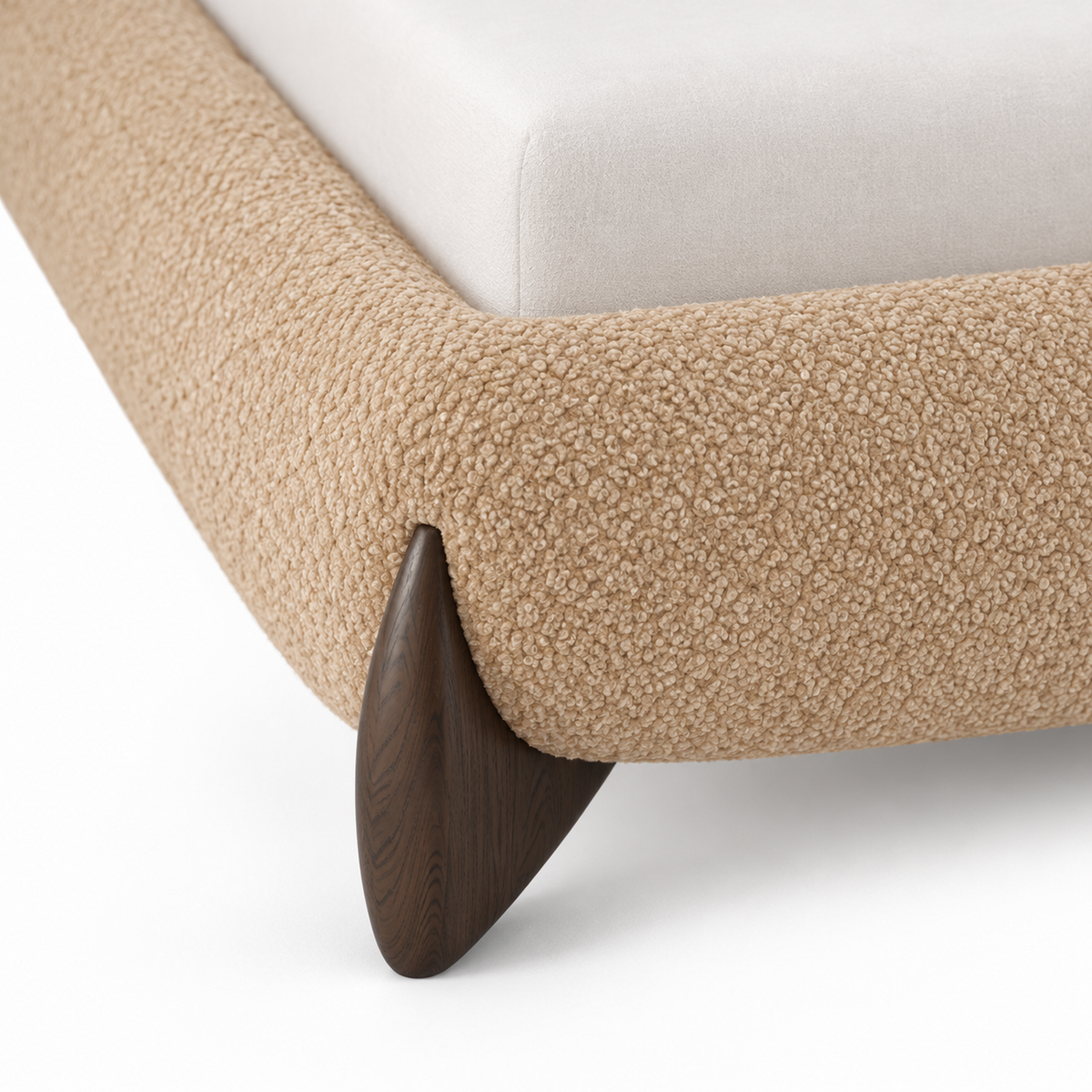 Close view of a front corner showing the boucle rail meeting a small smoked-oak wood foot on the Orma bed frame
