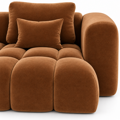 Close view of the bubble-tufted velvet cushions, the rounded arm and a scatter pillow on the Nube sofa